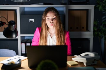 Wall Mural - Young caucasian woman working at the office at night making fish face with lips, crazy and comical gesture. funny expression.