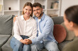 Millennial spouses share hug on couch in psychologist's office