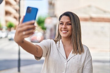 Canvas Print - Young hispanic woman smiling confident making selfie by the smartphone at street