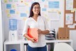 © Krakenimages.com - Young beautiful hispanic woman business worker smiling confident holding binder at office