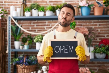 Canvas Print - Handsome hispanic man working at florist holding open sign looking at the camera blowing a kiss being lovely and sexy. love expression.