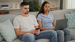 © Krakenimages.com - Beautiful couple in love, sitting together on living room sofa at home, engrossed in technology. man and woman using their laptop and smartphone, working and texting online.