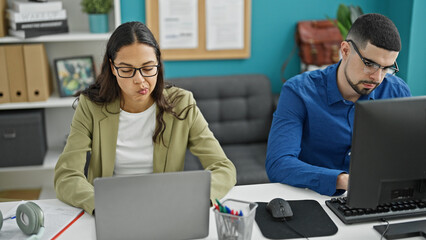 Wall Mural - Two lifestyle professionals, man and woman coworkers, working together using computer and laptop in an elegant office interior