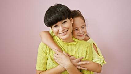 Wall Mural - Confident mother and daughter sharing a lovely, happy hug while smiling and standing together over an isolated pink background, expressing a casual lifestyle full of fun, joy and positive vibes.