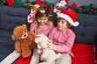 © Krakenimages.com - Brother and sister playing with teddy bears sitting on sofa by christmas decoration at home