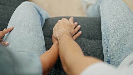 Poster - Man and woman couple sitting on sofa with hands together at home