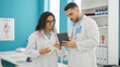 © Krakenimages.com - Man and woman doctors standing together using touchpad taking notes at the clinic