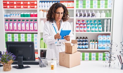 Poster - Middle age woman pharmacist using touchpad holding pills bottle at pharmacy