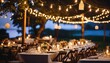 Cozy, ambient outdoor event in the evening - festive string lights, marquee tents, rustic wooden tables, lanterns, floral centerpieces