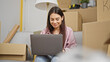 © Krakenimages.com - Young beautiful hispanic woman using laptop sitting on sofa at new home