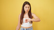© Krakenimages.com - Young beautiful hispanic woman looking watch with relaxed expression over isolated yellow background