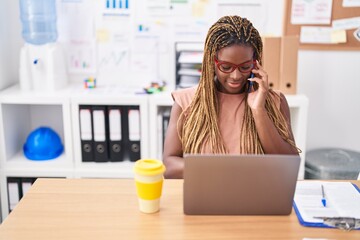 Sticker - African american woman business worker using laptop talking on smartphone at office