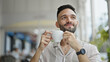 © Krakenimages.com - Young hispanic man holding cup of coffee smiling at coffee shop terrace