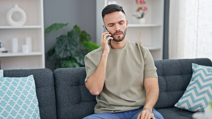 Canvas Print - Young hispanic man talking on the smartphone with serious expression at home