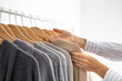 Women's hands choose neutral clothes from a hanger. White, beige and gray jersey.