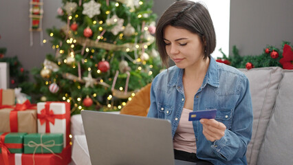 Young caucasian woman doing christmas online shopping with laptop at home