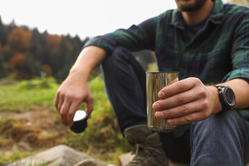 Canvas Print - Man with metallic thermo tumbler in nature, closeup