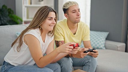 Sticker - Beautiful couple playing video game sitting on sofa at home