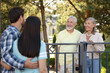 © New Africa - Friendly relationship with neighbours. Young family talking to elderly couple near fence outdoors