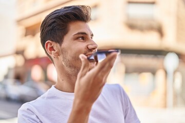 Wall Mural - Young hispanic man smiling confident talking on the smartphone at park