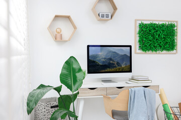 Canvas Print - Green artificial plant wall panel and desk with computer in light room. Interior design