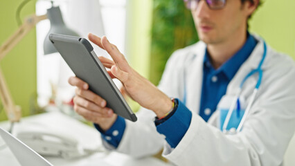 Poster - Young hispanic man doctor using touchpad working at the clinic