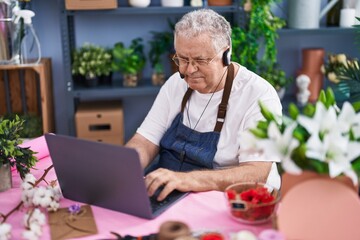 Poster - Middle age grey-haired man florist using laptop and headphones at florist