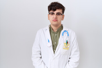 Wall Mural - Young non binary man wearing doctor uniform and stethoscope depressed and worry for distress, crying angry and afraid. sad expression.