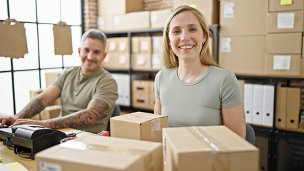 Wall Mural - Man and woman ecommerce business workers sitting together smiling at office