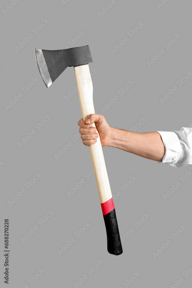 Male hand holding axe on grey background