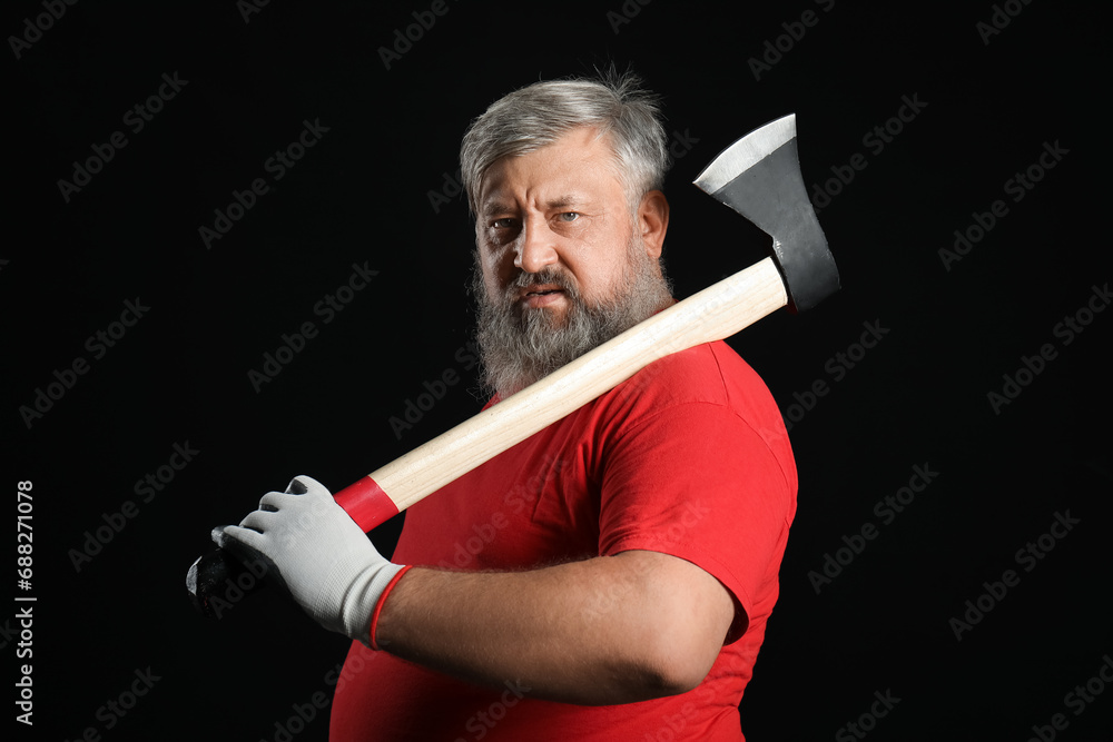 Portrait of mature lumberjack with axe on black background