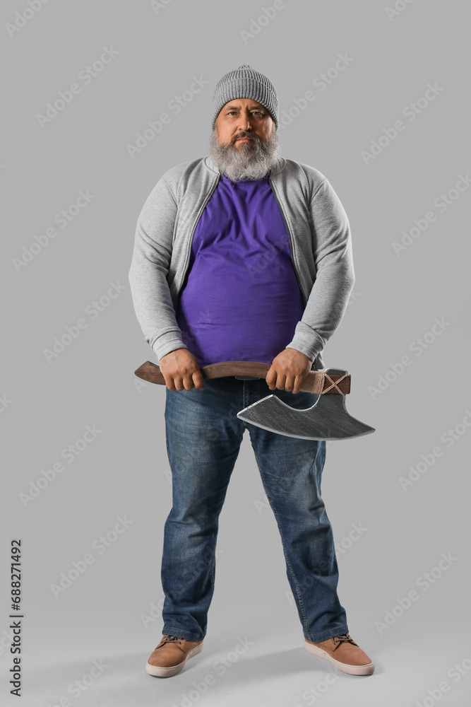 Portrait of mature man with axe on grey background