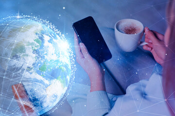Wall Mural - global network. woman holding smartphone and cup of coffee, closeup. digital image of earth