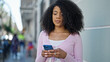 © Krakenimages.com - African american woman using smartphone with serious expression at street
