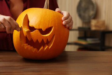 Wall Mural - Woman carving pumpkin for Halloween at wooden table indoors, closeup