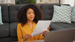 © Krakenimages.com - African american woman using laptop reading document at home