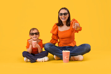 Sticker - Beautiful mother and her cute little daughter in 3D glasses with buckets of popcorn on yellow background