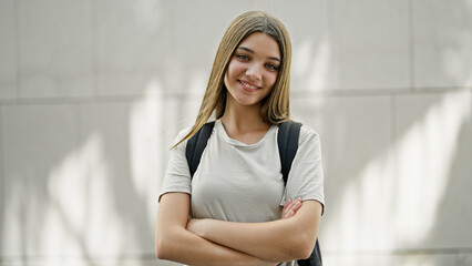 Young beautiful girl student wearing backpack standing with arms crossed gesture smiling over isolated white background