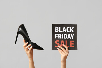 Canvas Print - Female hands holding poster with text BLACK FRIDAY SALE and stylish shoes on grey background