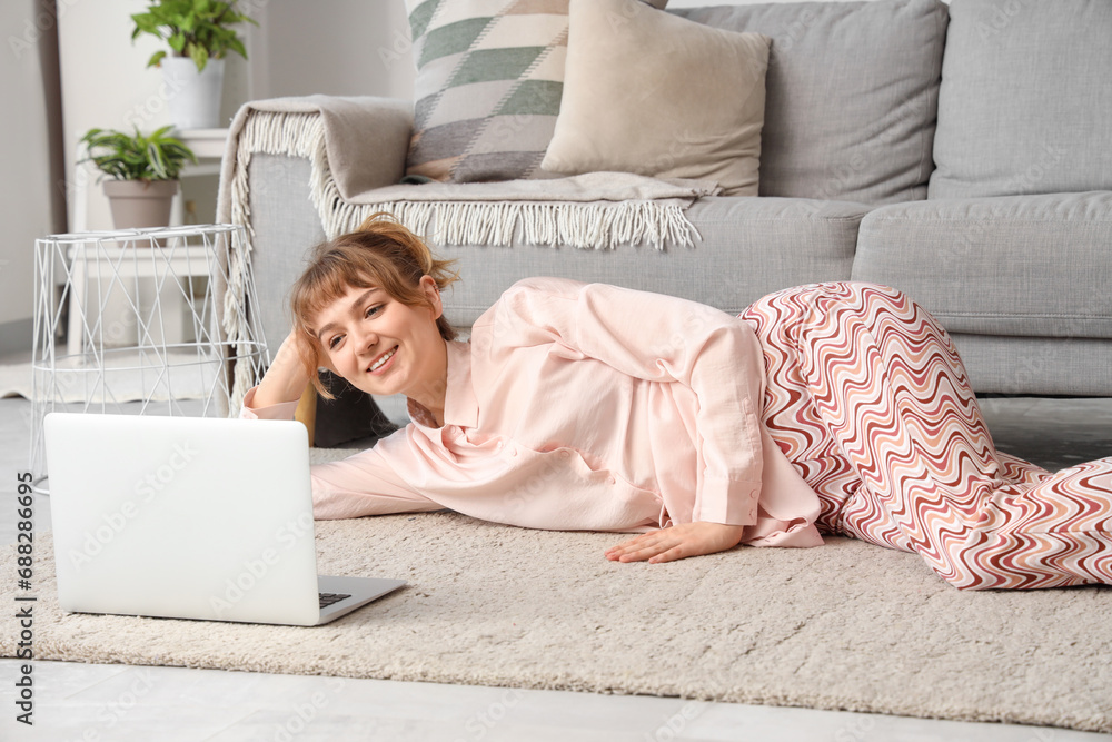 Young woman with laptop relaxing on floor at home