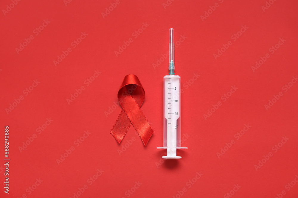 Red ribbon with syringe on color background. AIDS Day concept