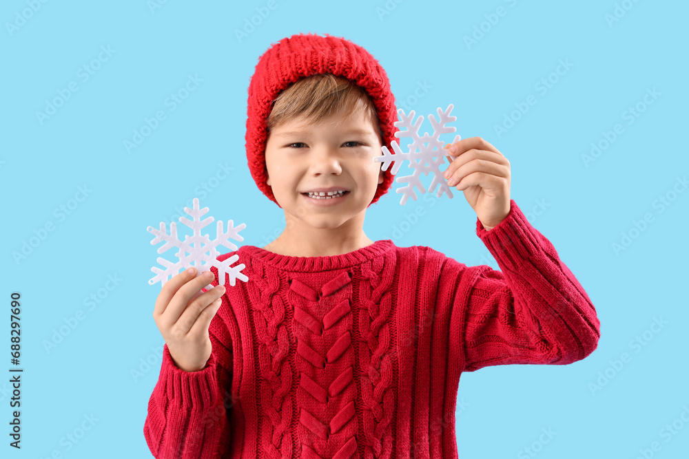 Cute little boy with snowflakes on blue background. Christmas celebration