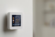 Thermostat displaying temperature in Fahrenheit scale and different icons. Smart home device on white wall, space for text