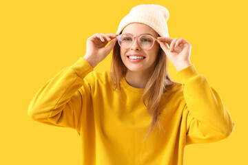 Wall Mural - Young woman in eyeglasses on yellow background