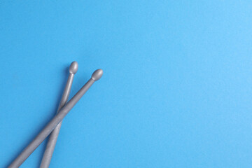 Wall Mural - Two gray drum sticks on light blue background, top view. Space for text