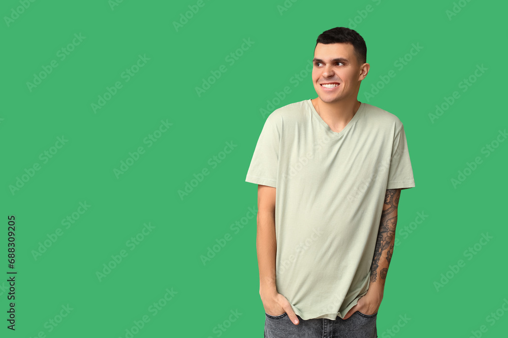 Handsome ashamed young man on green background