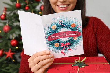 Canvas Print - Happy woman with gift box reading Christmas greeting card at home, closeup