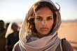 Serious young muslim middle eastern woman wearing a religious headscarf walking in the desert looking at the camera