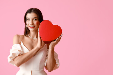 Wall Mural - Happy young woman with kiss marks on her face and gift box on pink background