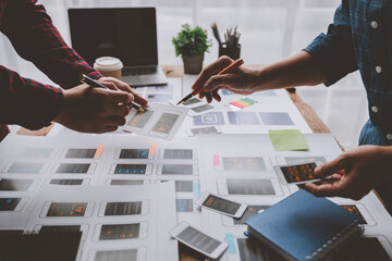 ux developers and ui designers brainstorm on tabletop mobile app layout design planning design color coding at modern office Creative digital development agency.